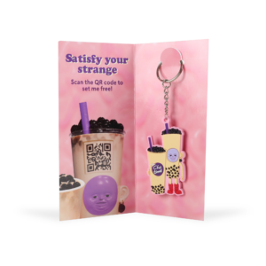 pink packaging with 'satisfy your strange' character that is in a key ring design
